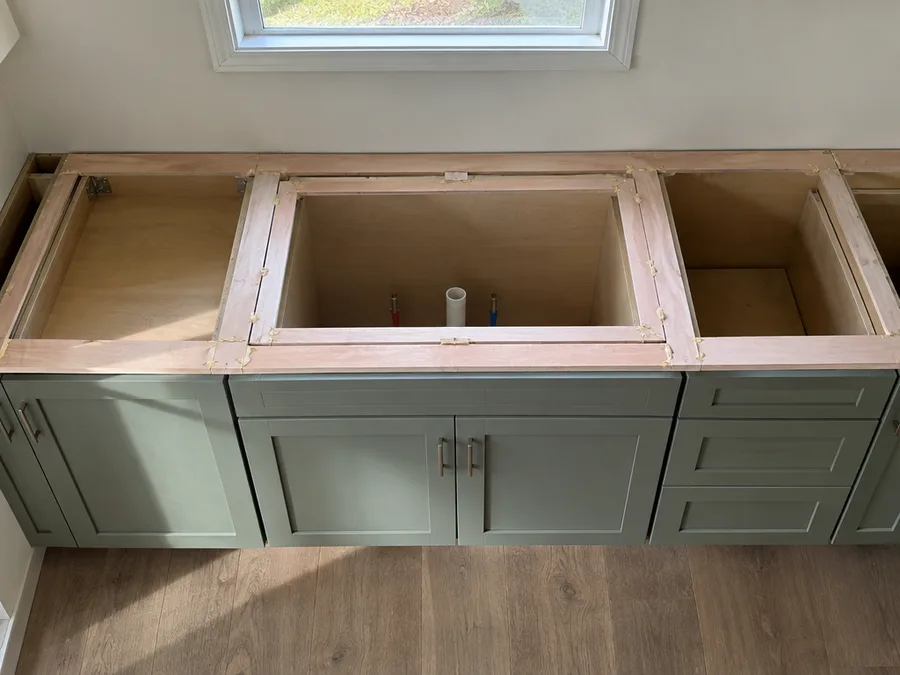 A countertop template of thin wood strips glued into an outline on new base cabinets with no countertop yet